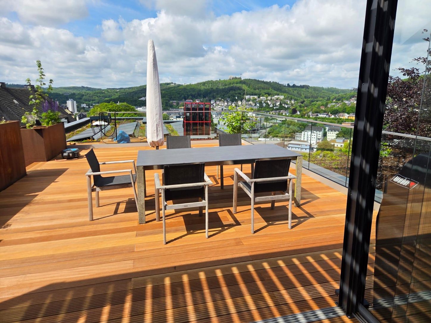 Roof terrace with Bangkirai decking, glass balustrade and a view across the valley